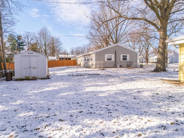 snow covered rear of property featuring a storage unit