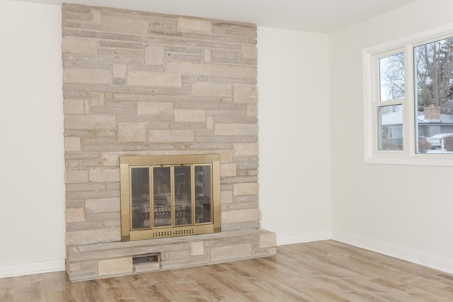 room details featuring a stone fireplace and wood-type flooring