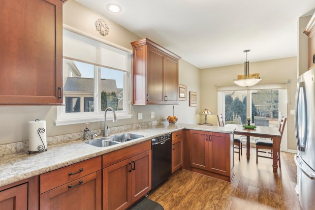 kitchen featuring stainless steel refrigerator, dishwasher, sink, dark wood-type flooring, and decorative light fixtures