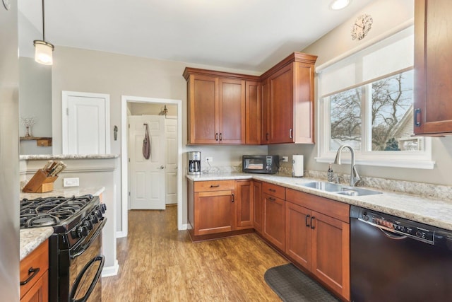 kitchen with sink, hanging light fixtures, light stone counters, light hardwood / wood-style floors, and black appliances