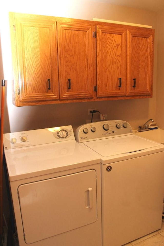 washroom featuring light tile patterned flooring, washing machine and clothes dryer, and cabinets