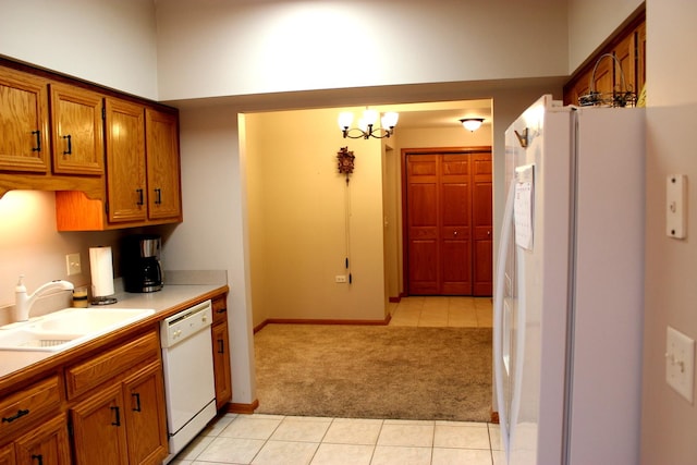 kitchen with sink, white appliances, light carpet, and a chandelier