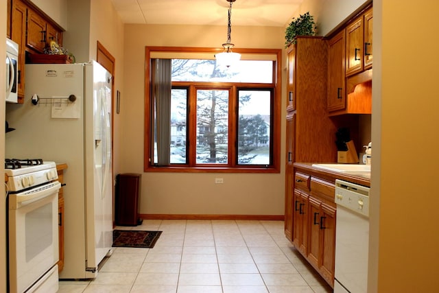 kitchen featuring decorative light fixtures, light tile patterned floors, sink, and white appliances