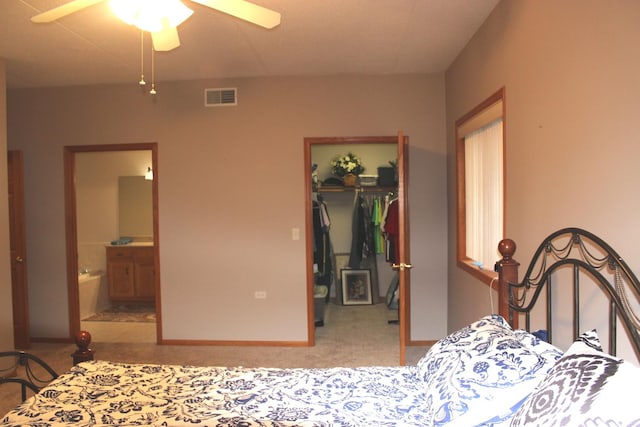 carpeted bedroom with ceiling fan, ensuite bathroom, a closet, and a walk in closet