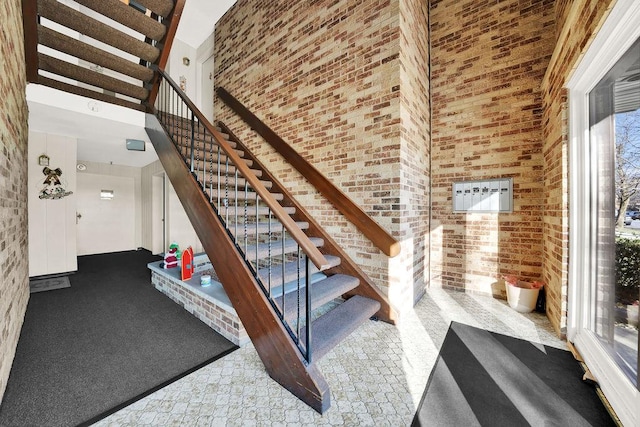 stairs with a high ceiling and brick wall