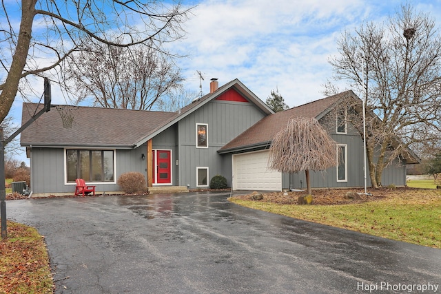 view of front of property featuring a front lawn, central AC unit, and a garage