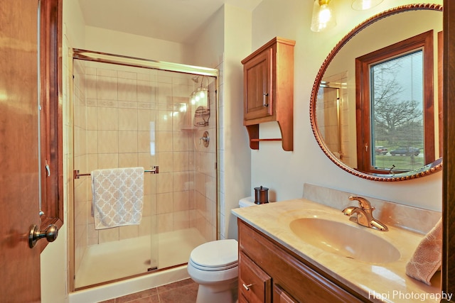 bathroom with tile patterned floors, toilet, an enclosed shower, and vanity