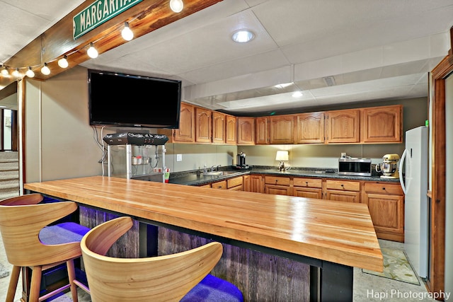 kitchen with butcher block countertops, sink, and white fridge