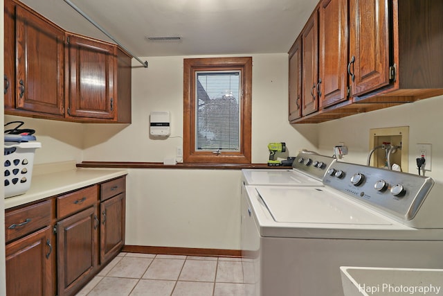 laundry room featuring washer and dryer, light tile patterned flooring, and cabinets