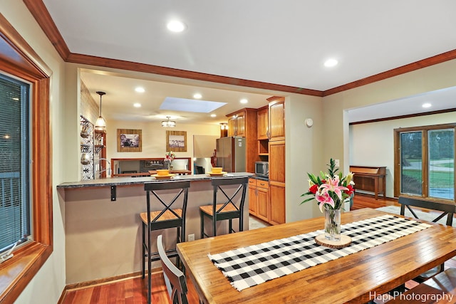 dining room featuring a skylight, crown molding, and light hardwood / wood-style floors