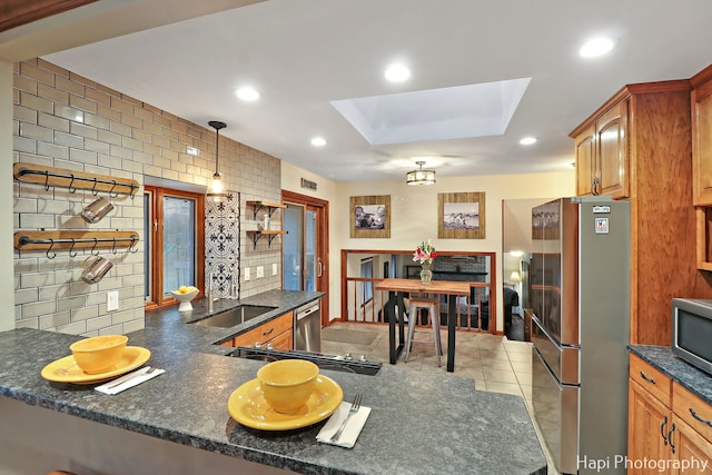 kitchen featuring a skylight, sink, tasteful backsplash, kitchen peninsula, and appliances with stainless steel finishes