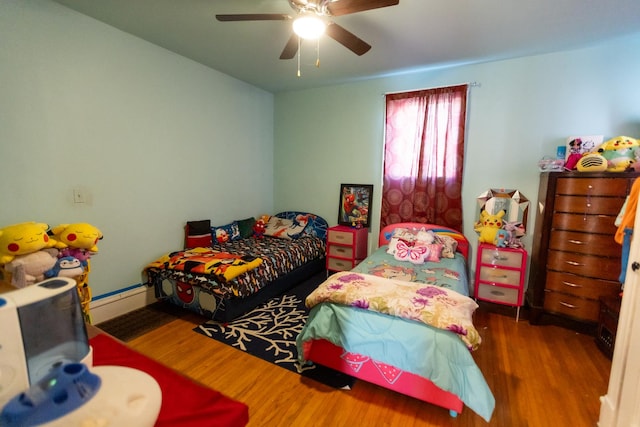 bedroom with a baseboard heating unit, ceiling fan, and dark wood finished floors