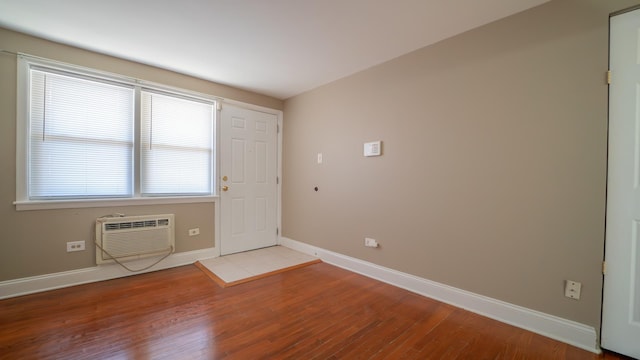 spare room featuring plenty of natural light, a wall unit AC, and light hardwood / wood-style flooring