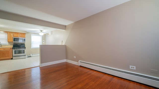 interior space with ceiling fan, light hardwood / wood-style floors, and a baseboard heating unit