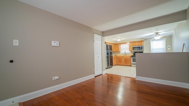 unfurnished living room featuring ceiling fan, sink, and light hardwood / wood-style flooring