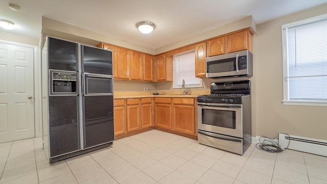 kitchen with appliances with stainless steel finishes, a baseboard radiator, and light tile patterned floors