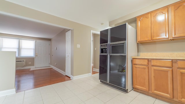 kitchen with black fridge, light tile patterned floors, and a wall unit AC