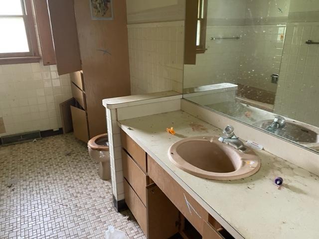 bathroom with vanity, toilet, and tile walls