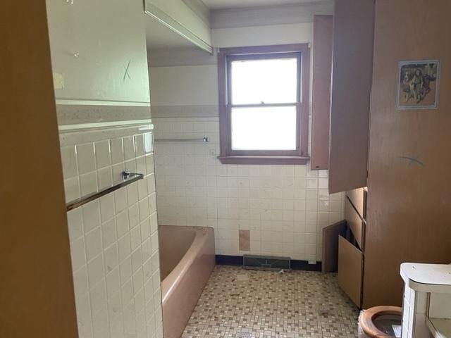 bathroom featuring a bathtub, vanity, tile walls, and toilet