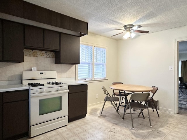 kitchen featuring ceiling fan, white gas range oven, and dark brown cabinets