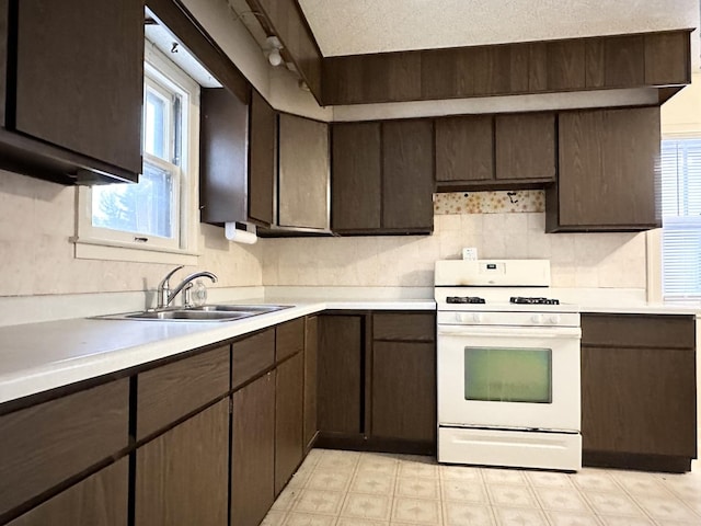 kitchen with sink, a textured ceiling, gas range gas stove, and dark brown cabinetry