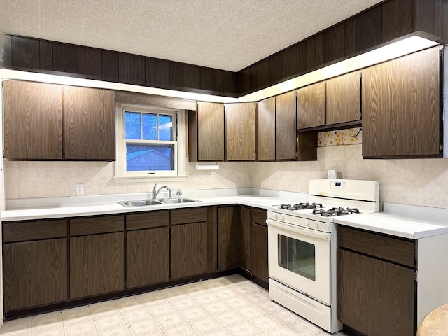 kitchen with dark brown cabinetry, gas range gas stove, and sink