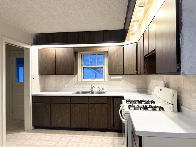 kitchen with sink, dark brown cabinets, gas range gas stove, and a textured ceiling