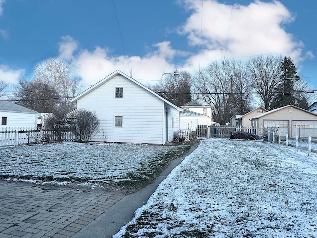 yard layered in snow featuring a garage and an outbuilding