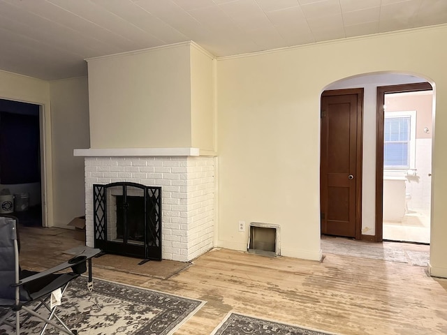 living room with a fireplace, light wood-type flooring, and ornamental molding