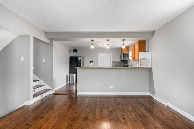 kitchen with light stone counters, appliances with stainless steel finishes, tasteful backsplash, dark hardwood / wood-style flooring, and kitchen peninsula