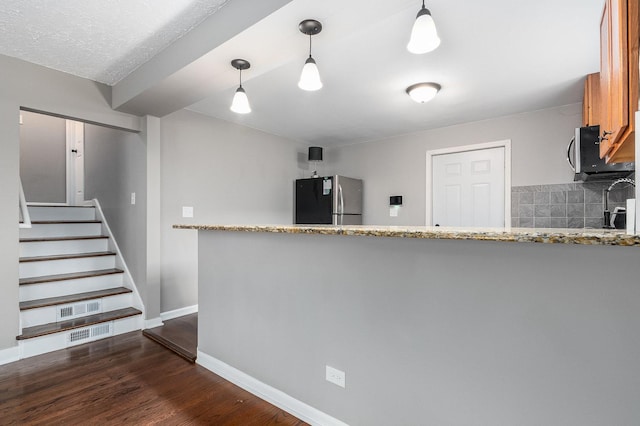 kitchen with pendant lighting, decorative backsplash, stainless steel appliances, and dark wood-type flooring