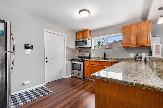 kitchen with decorative backsplash, appliances with stainless steel finishes, dark wood-type flooring, sink, and decorative light fixtures