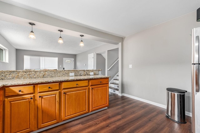 kitchen featuring light stone countertops, dark wood-type flooring, hanging light fixtures, and a textured ceiling