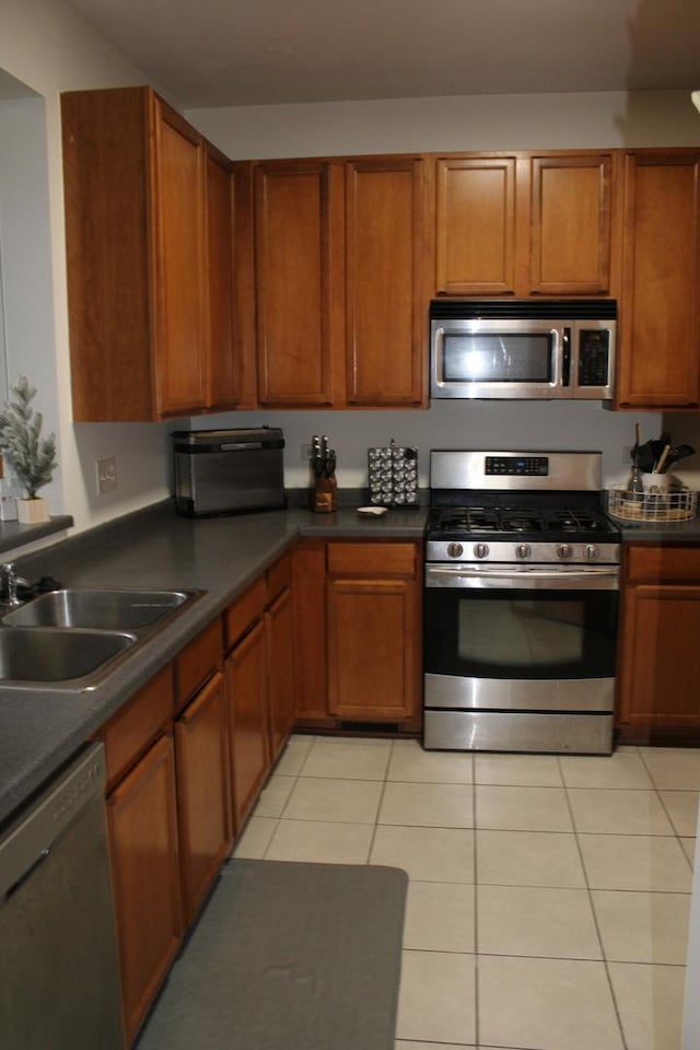 kitchen with stainless steel appliances, sink, and light tile patterned floors