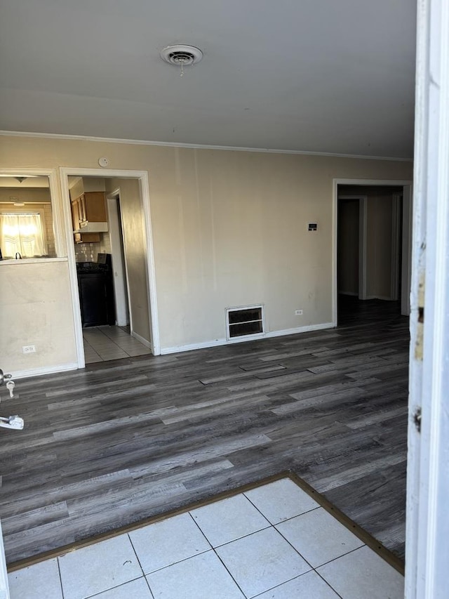 empty room featuring dark wood-type flooring and ornamental molding