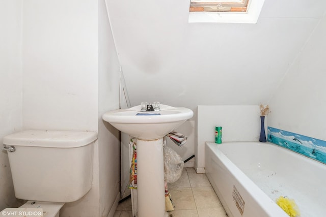 bathroom with tile patterned floors, sink, a skylight, toilet, and a tub to relax in