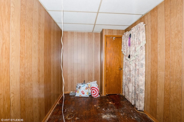 interior space with a paneled ceiling and wooden walls