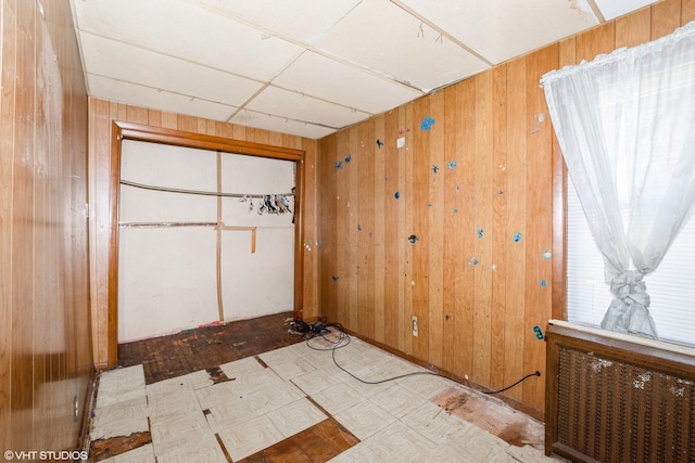 empty room featuring a paneled ceiling and wooden walls