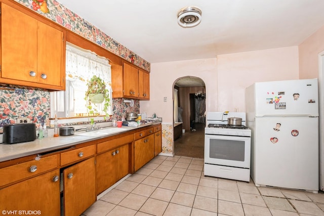 kitchen with light tile patterned flooring, white appliances, backsplash, and sink