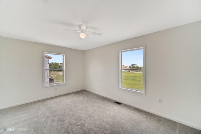 empty room with carpet floors, a wealth of natural light, and ceiling fan