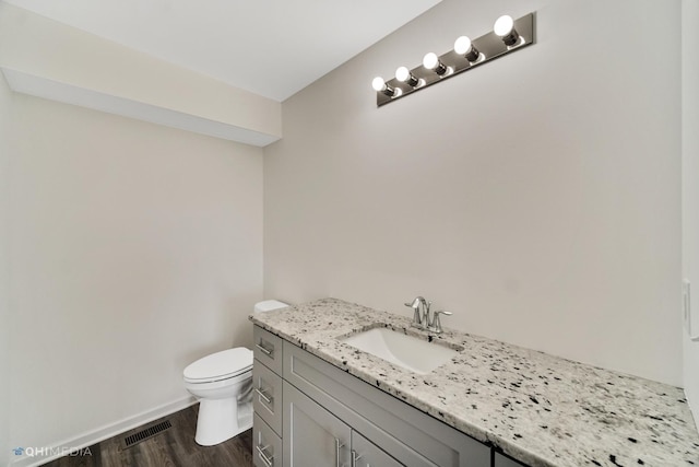 bathroom with wood-type flooring, vanity, and toilet