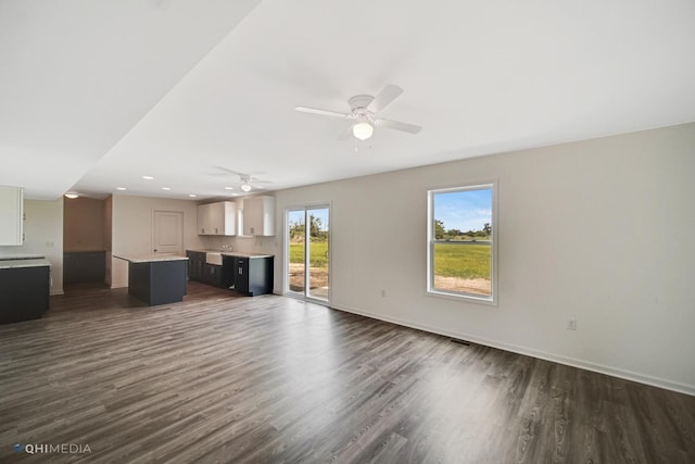 unfurnished living room with dark hardwood / wood-style floors and ceiling fan