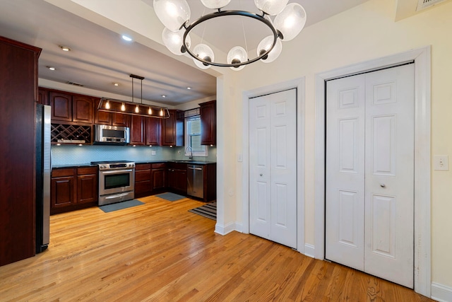 3022 N Hamilton Ave, Chicago, IL 60618 - kitchen featuring light wood finished floors, stainless steel appliances, an inviting chandelier, a sink, and decorative backsplash
