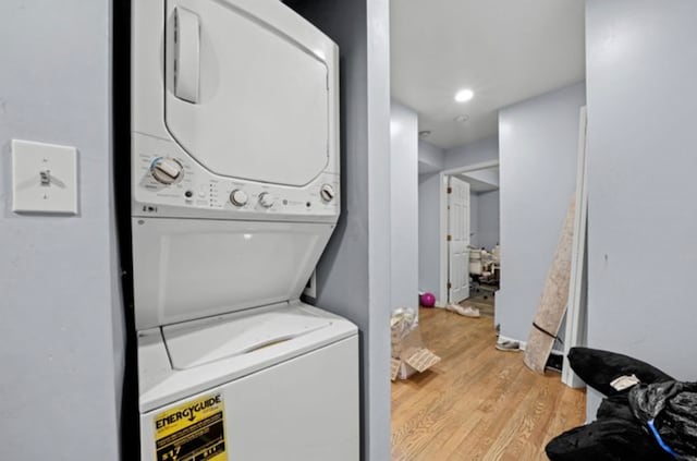 clothes washing area featuring light hardwood / wood-style flooring and stacked washer / dryer