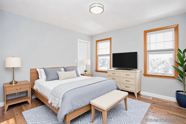 bedroom with light wood-style flooring, visible vents, and baseboards