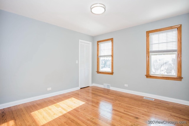 spare room featuring baseboards, visible vents, and light wood-style flooring