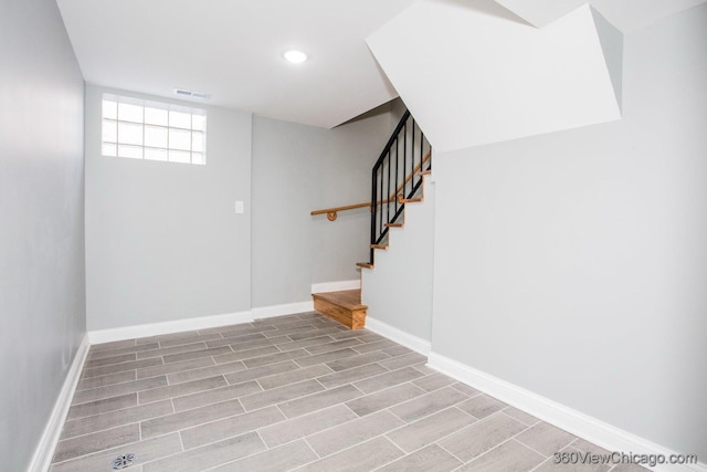 basement featuring light wood-style floors, baseboards, stairs, and visible vents