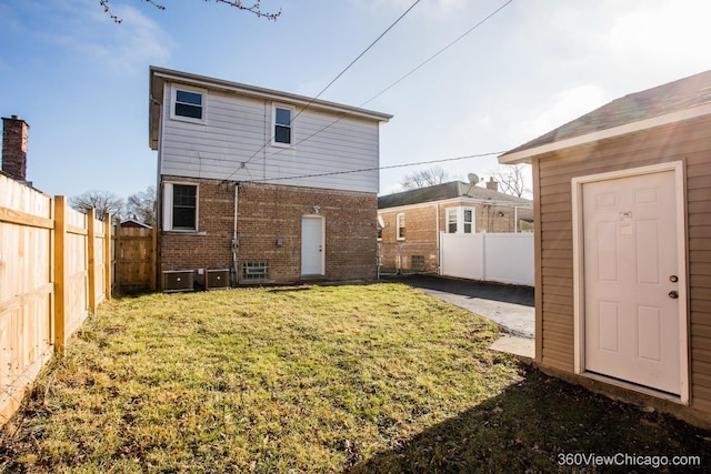 back of house featuring brick siding, a yard, a fenced backyard, and central AC unit