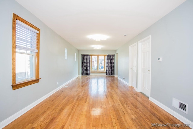 empty room featuring light wood-type flooring, visible vents, and baseboards