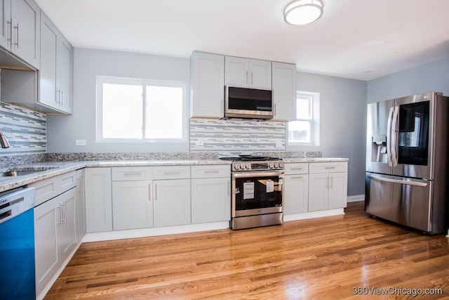 kitchen with backsplash, sink, plenty of natural light, light hardwood / wood-style floors, and stainless steel appliances